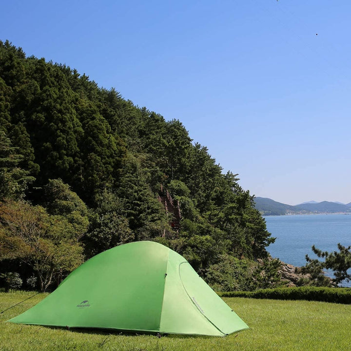 Naturehike Cloud Up Base three person green backpacking tent set up on grassy outdoor campsite, stable freestanding design for hiking, camping, and travel adventures.